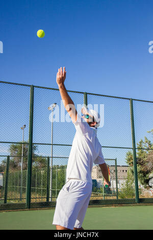 Profi-Tennisspieler tut ein Kick-Tennis auf dem Tennisplatz an einem sonnigen Sommermorgen. Das ist in der Sportswear gekleidet. Stockfoto