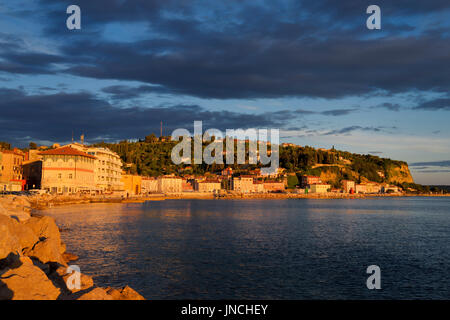 Rotes Licht bei Sonnenuntergang an der Adria-Küste in Piran Slowenien Hafen und Hügel mit Blick auf Altstadt Stockfoto