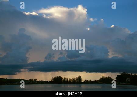 Dunkelblau, Grau und Gelb Regen Wolken Nachbarschaft auf See am späten Nachmittag in der Nähe von Sunset Stockfoto