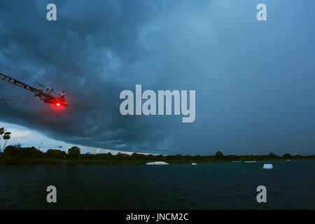 Gigantische regen Sturm Cloud nähern Quiet Waters Park Ski Rixen See in der Abenddämmerung mit Menschen zur Festsetzung Ski Rixen Pully System oben ROT BELEUCHTET Stockfoto