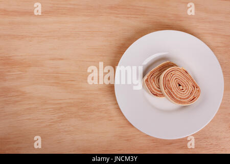 Biskuitroulade (Kuchen) mit roten Beeren Marmelade auf Holztisch. Selektiven Fokus. Textfreiraum Stockfoto