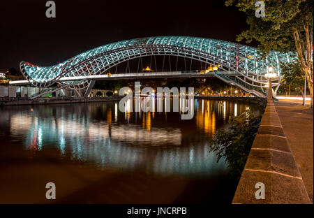 Nacht-Blick auf die Brücke des Friedens über Fluss Kura, Tiflis, Georgien Stockfoto