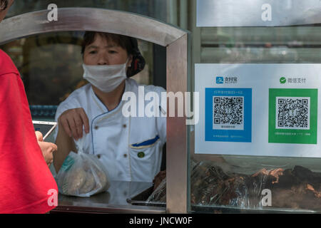 Die Leute kaufen Snacks bei einer normalen Lebensmittelgeschäft QR-Code mit Ihrem Handy, mit Alipay, WeChat Pay in Peking, China. 30. Juli 2017 Stockfoto