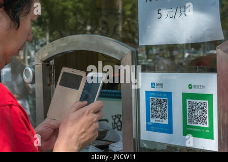 Die Leute kaufen Snacks bei einer normalen Lebensmittelgeschäft QR-Code mit Ihrem Handy, mit Alipay, WeChat Pay in Peking, China. 30. Juli 2017 Stockfoto