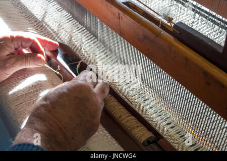 Traditionelle Hand Weaver Eddie Doherty Fäden einen Shuttle an seinem Webstuhl in Ardara, County Donegal, Irland Stockfoto