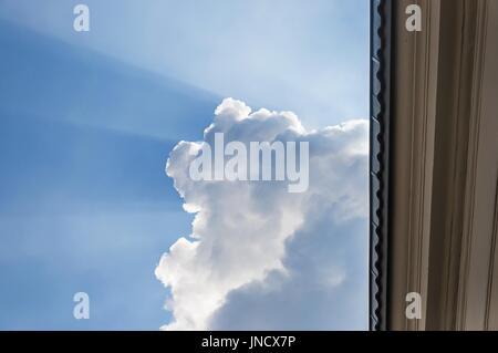 große Wolke mit Sonnenstrahlen, die sich aus es mit Teil-o-Fassade des Gebäudes Stockfoto