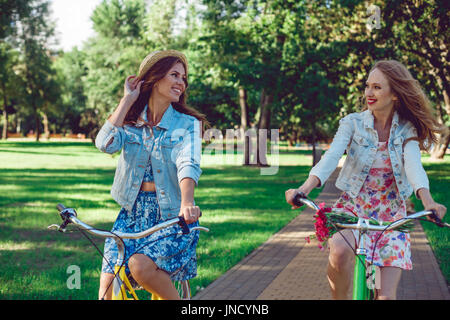 Zwei junge Freundinnen ihr Fahrrad in den Park fahren. Stockfoto