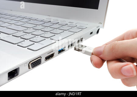 Hand, die weiße USB-Kabel in Laptop isoliert auf weißem Hintergrund einfügen Stockfoto