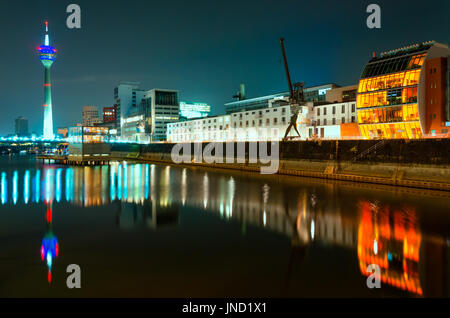 Nachtaufnahme des Rheins in der Nacht in Düsseldorf. Blick vom Medienhafen am Rheinturm Turm, Cafe am Wasser und Hafen-Kran mit Spiegelungen im Wasser; Stockfoto