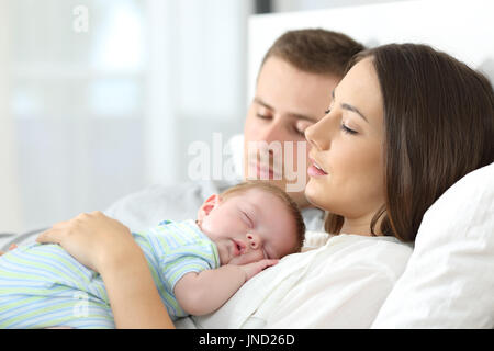 Porträt von müde Eltern schlafen auf einem Bett zu Hause mit ihrem baby Stockfoto