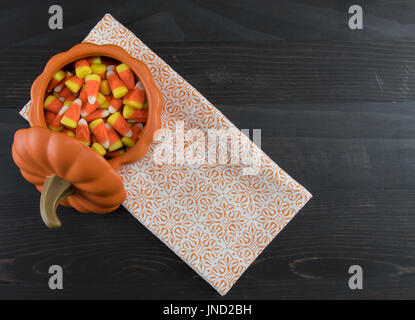Candy Corn in Keramik Kürbis mit Serviette auf dunkle Tischplatte Stockfoto
