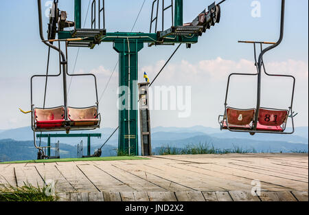 leere Skilift mit roten Stühlen auf einem Hügel Gymba. Karpaten Bergrücken Borzhava, Ukraine. Schöne Berglandschaft mit klarer Himmel Stockfoto