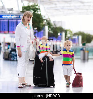 Familie am Flughafen vor dem Flug. Mutter und Kinder an Bord am Abflug-Gate des modernen internationalen Terminals warten. Reisen und fliegen mit childr Stockfoto