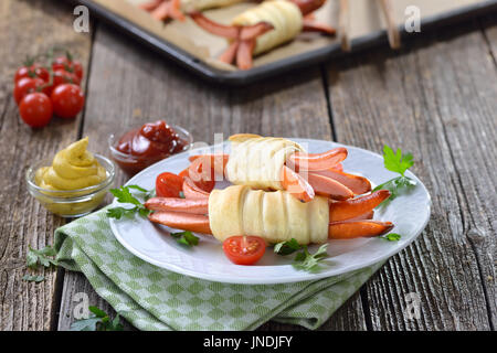 Gebackene Wiener Würstchen umhüllt mit Blätterteig frisch aus dem Ofen, oft als ein Kindermenü serviert Stockfoto