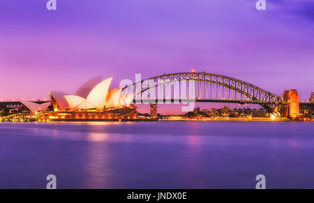 Sydney, Australien - 11. Juli 2015: Sydney Opera House und Harbour Brücke bei Sonnenuntergang gegen bunte Magenta Himmel und verschwommen, reflektierenden Wasser des Sydne Stockfoto