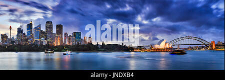 Breites Panorama von Sydney CBD Cityline aus Domäne Parkanlage in Richtung Royal Botanic Gardens und Bürotürmen Geschäft bei Sonnenuntergang mit Beleuchtung. Stockfoto