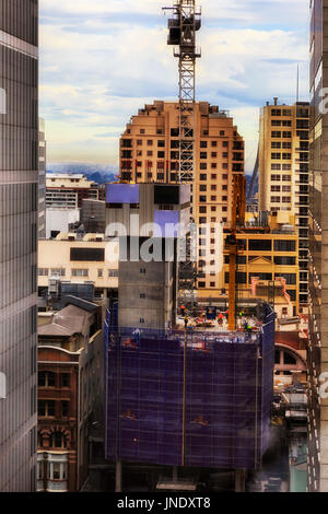 Baustelle der steigenden Wolkenkratzer Gebäude Stadt Sydney CBD. Handwerker-Arbeitnehmer bei der Arbeit mit Baumaschinen, Schwertransporte und Kran Stockfoto