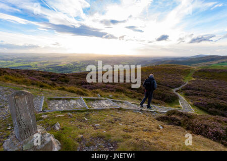 Ein männlicher Hügel Walker Heimkehr entlang der Hügel Clwydian Palette an der Grenze von Denbighshire und Flintshire, wenn die Sonne der Abstieg über die Vale Clwyd beginnt Stockfoto