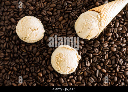 Kugeln von hausgemachter Kaffee-Eis und Eis auf ganz dunkel gerösteten Kaffeebohnen. Stockfoto