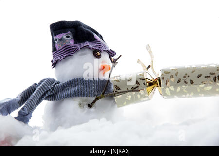 Niedlichen Schneemann ziehen einen Cracker, mit einem Hut und Schal im Winter zu Weihnachten Stockfoto