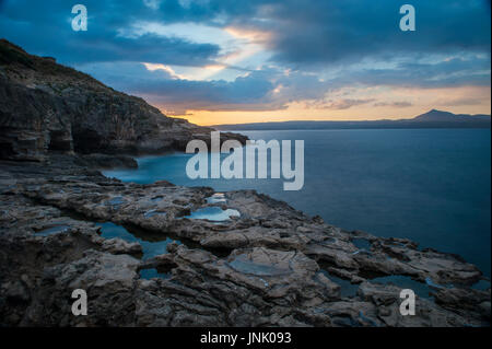 Sonnenuntergang auf einer felsigen Bucht auf Kreta mit rauhem Wasser und Wellen Stockfoto