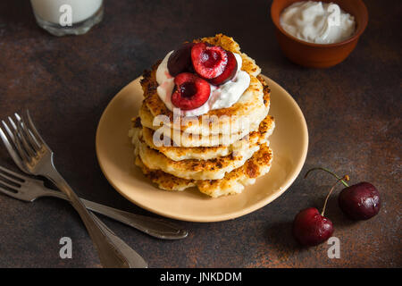 Rustikale hausgemachten Quark Pfannkuchen zum Frühstück, Landhausstil mit Joghurt-Sauce und Kirsche. Gesundes Essen rustikal, Pfannkuchen Quark. Stockfoto