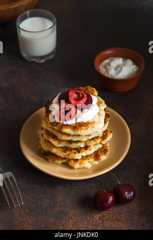 Rustikale hausgemachten Quark Pfannkuchen zum Frühstück, Landhausstil mit Joghurt-Sauce und Kirsche. Gesundes Essen rustikal, Pfannkuchen Quark. Stockfoto