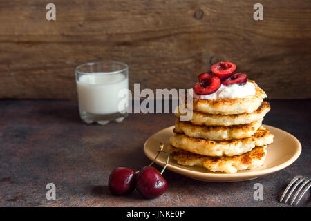 Rustikale hausgemachten Quark Pfannkuchen zum Frühstück, Landhausstil mit Joghurt-Sauce und Kirsche. Gesundes Essen rustikal, Pfannkuchen Quark. Stockfoto