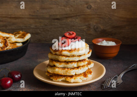 Rustikale hausgemachten Quark Pfannkuchen zum Frühstück, Landhausstil mit Joghurt-Sauce und Kirsche. Gesundes Essen rustikal, Pfannkuchen Quark. Stockfoto
