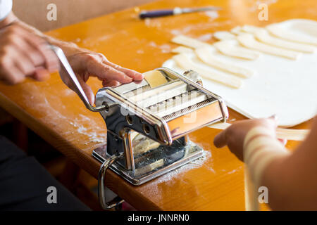 Mann, der hausgemachten Pasta zu Hause mit einer Maschine Stockfoto