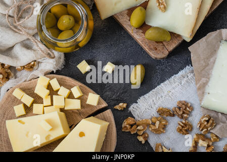 Käseplatte verschiedener Arten von Hartkäse (Schwedisch, Spanisch Manchego, italienischen Pecorino Toscano) geschnitten und mit grünen Oliven im Glas gehackt Stockfoto