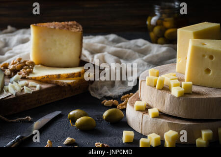 Käseplatte gehackte Schwedische harten Käse in Scheiben geschnitten und Spanischer Manchego und Italienischen pecorino Toscano) auf Brettern, mit grünen Oliven im Glas Stockfoto