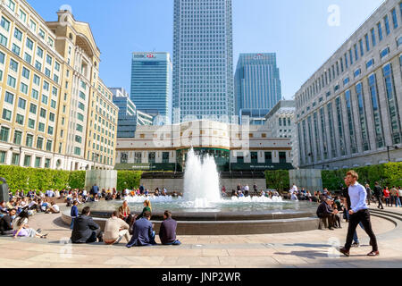 London, UK - 10. Mai 2017 - Cabot Square im Canary Wharf vollgepackt mit Menschen genießen den sonnigen Tag mit high-Rise Bürohaus im Hintergrund Stockfoto