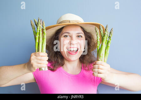 Close-up Portrait lustig überrascht Frau ist Spargel vor ihr Gesicht halten. Stockfoto