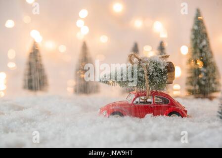 Kleines rotes Auto Spielzeug mit Weihnachtsbaum im Schnee bedeckt Miniatur Wald Stockfoto