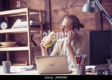 Freelancer telefonieren, halten große Sandwich. Stockfoto