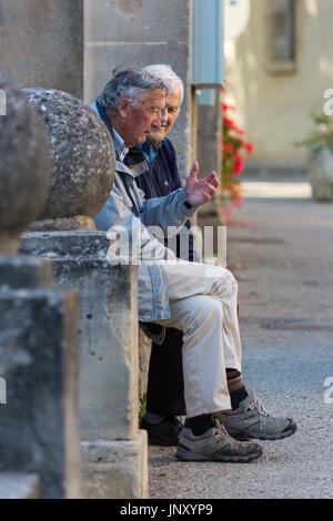 Lourmarin, Luberon, Provence, Frankreich - 9. Oktober 2015: Zwei ältere Männer chat auf Bank in der Straße in Lourmarin, Luberon, Provence, Frankreich. Stockfoto