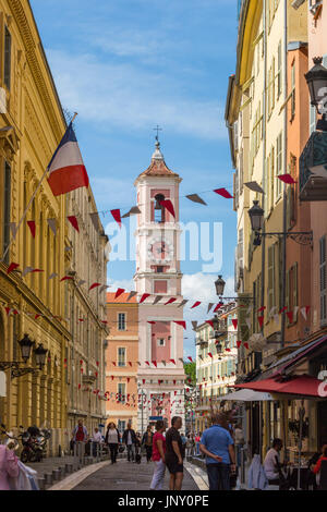 Nizza, Alpes-Maritimes Abteilung, Frankreich - 10. Oktober 2015: Straßenszene in Nizza an der Mittelmeerküste von Alpes-Maritimes im Südosten Frankreichs. Die rosa Clocktower des Palais Rusca in Ferne. Stockfoto