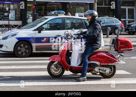 Paris. Frankreich - 27. Februar 2016: Mann auf Motorroller neben einem Polizeiauto auf einem Zebrastreifen auf Avenue Bosquet im 7. Arrondissement, Paris. Stockfoto