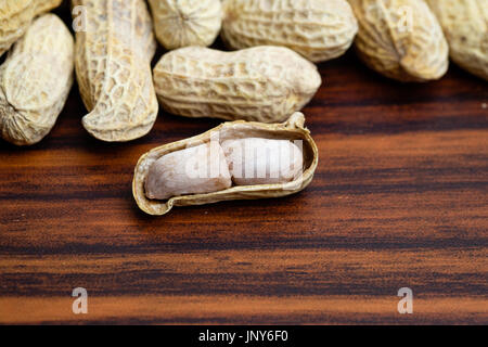 Erdnüsse auf Holztisch mit einer geöffneten Schale Stockfoto