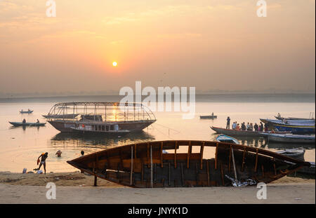 Sonnenaufgang über den Ganges, mit Booten auf dem Wasser und im Trockendock Stockfoto