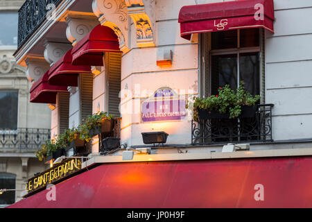 Paris, Frankreich - 2. März 2016: Le Saint Germain Restaurant Café mit roten Markisen, leuchtet am frühen Morgen mit noch auf. Stockfoto