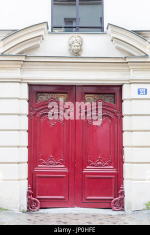 Paris, Frankreich - 2. März 2016: Rote Tür mit kunstvollen Schnitzereien und eleganten Bogen in Paris. Stockfoto