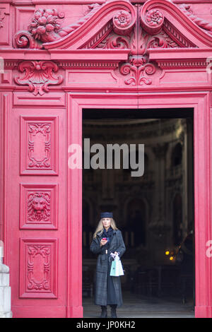 Paris, Frankreich - 2. März 2016: Elegante junge Frau mit Handy an der Tür der Kirche Saint-Paul-Saint-Louis im Marais, Paris Stockfoto