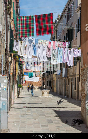 Venedig, Italien - 26. April 2012: Kleidung zum Trocknen auf Wäscheleinen gespannt zwischen Gebäuden im Castello Bezirk von Venedig. Stockfoto
