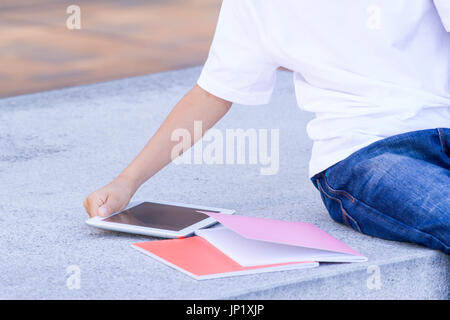 Die Hand des Kindes mit Tablet Computer und Bücher. Nahaufnahme Stockfoto