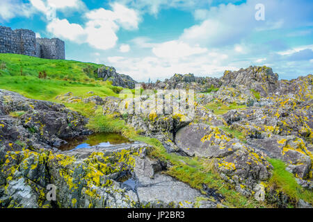 Querformat der Peel Hill felsigen Küste mit großen Mauer der Peel Schloss im Hintergrund, von der Insel Man Stockfoto