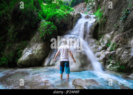 Mann Alleinreisende steht man vor einem Wasserfall im Dschungel. Stockfoto