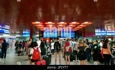 Prag, Tschechische Republik - 28. Juli 2017: Reisende warten auf einen Zug in Abflughalle und blicken auf eine Abfahrtstafel in Prag Hauptbahnhof statio Stockfoto