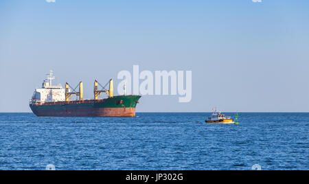 Bulk-Carrier. Große Ladung Schiff Segel auf dem Meer mit kleinen Lotsenboot Stockfoto